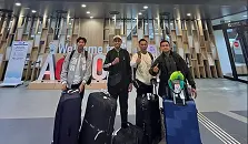 Empat pria mengenakan jaket kerja dan sepatu kasual berfoto di area luar gedung perkotaan.