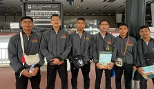 Tiga pria berseragam kerja berdiri di dalam gedung sambil memegang dokumen resmi.