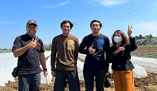 Sekelompok pria dan wanita berfoto di luar ruangan dengan latar langit biru dan area terbuka.